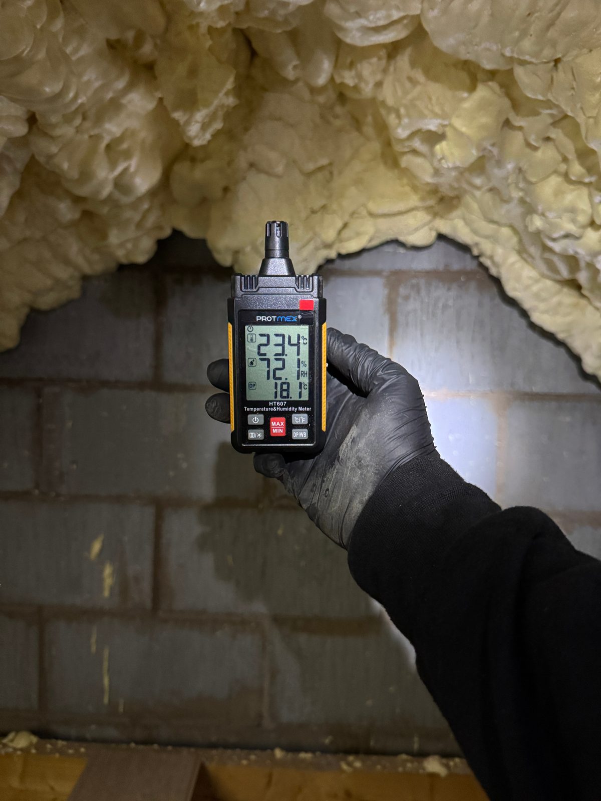 Independent spray foam loft inspection — calibrated psychrometer reading temperature, relative humidity and dew point at the loft apex beneath closed-cell spray foam