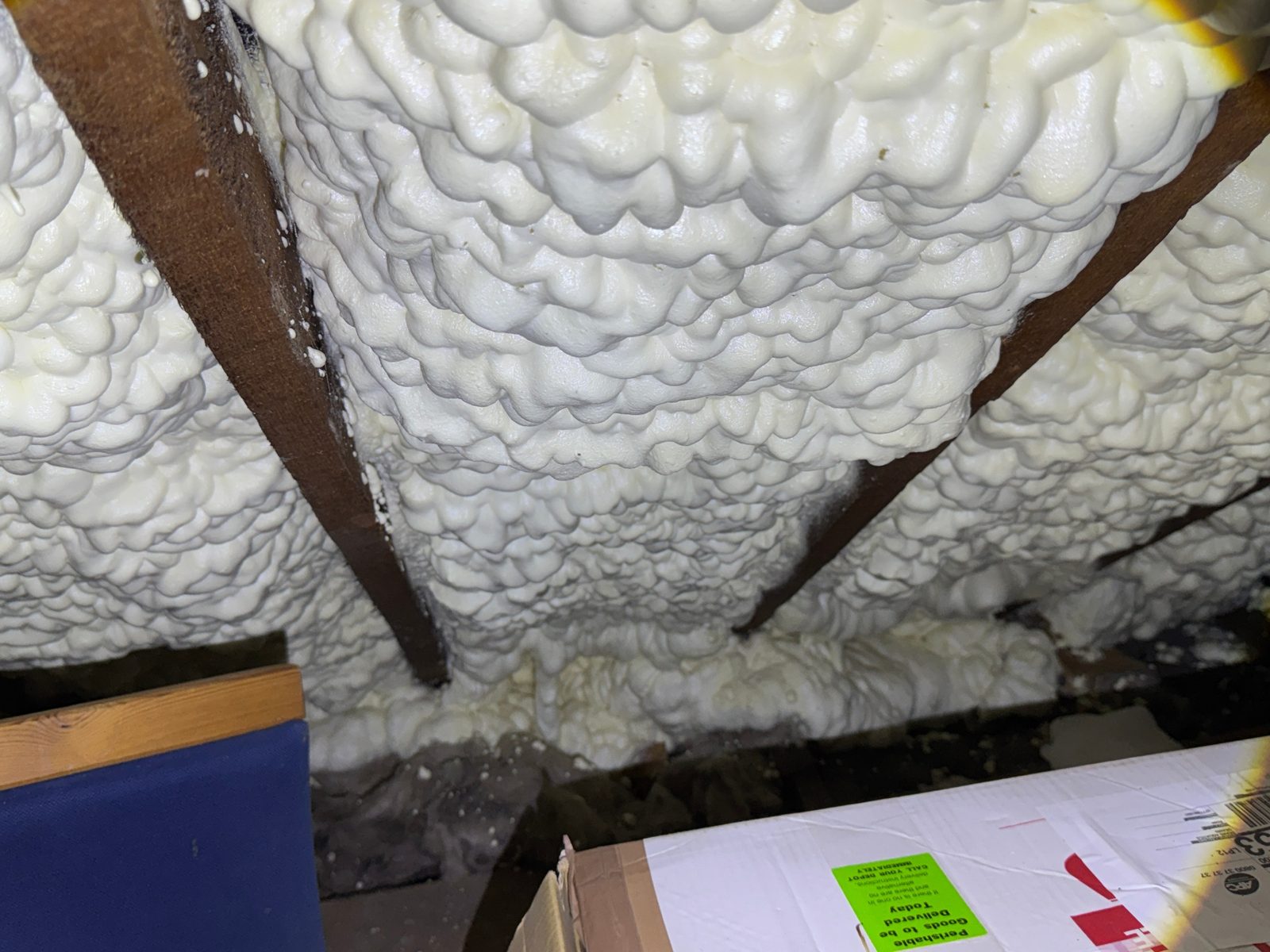 Independent spray foam loft inspection — thick open-cell spray foam sprayed between rafters on the underside of a pitched roof